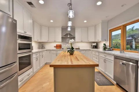 a kitchen with kitchen island granite countertop stainless steel appliances cabinets a sink and a counter top space