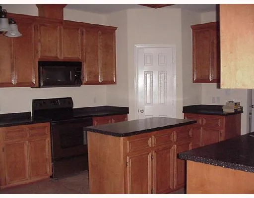 a kitchen with granite countertop a sink cabinets and stainless steel appliances