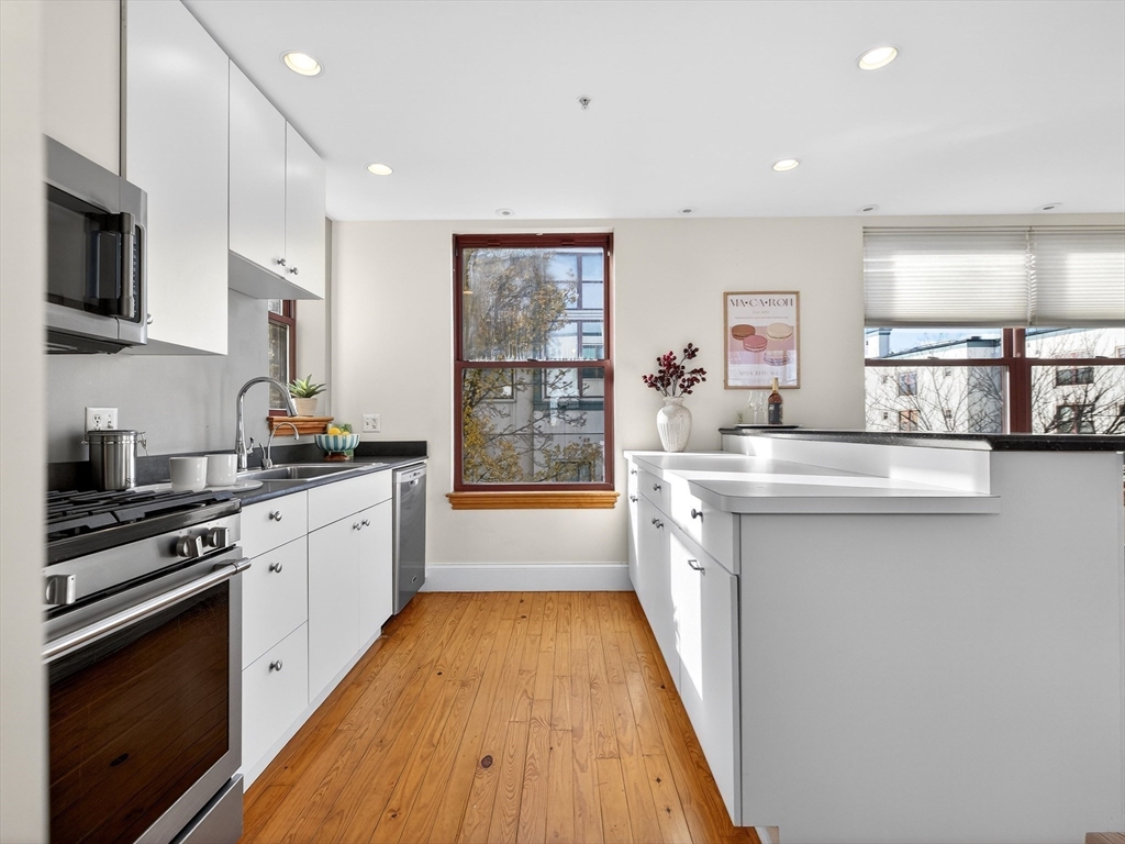 62-76 Cornwall Street, Unit 74 (E) Boston, MA 02130 - Photo 12 of 34 a kitchen with stainless steel appliances a sink stove and wooden floor