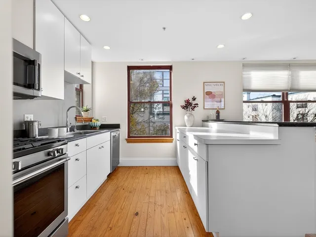a kitchen with stainless steel appliances a sink stove and wooden floor