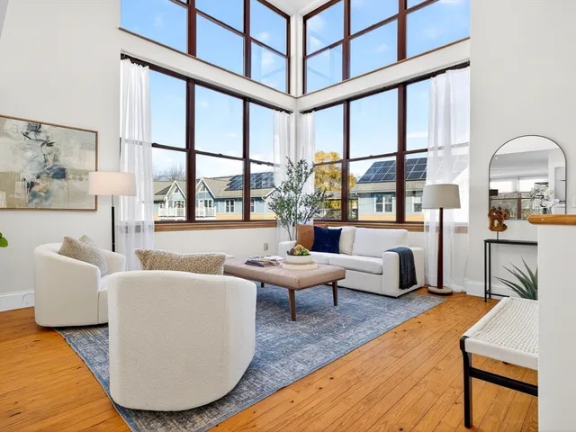 a living room with furniture large window and wooden floor