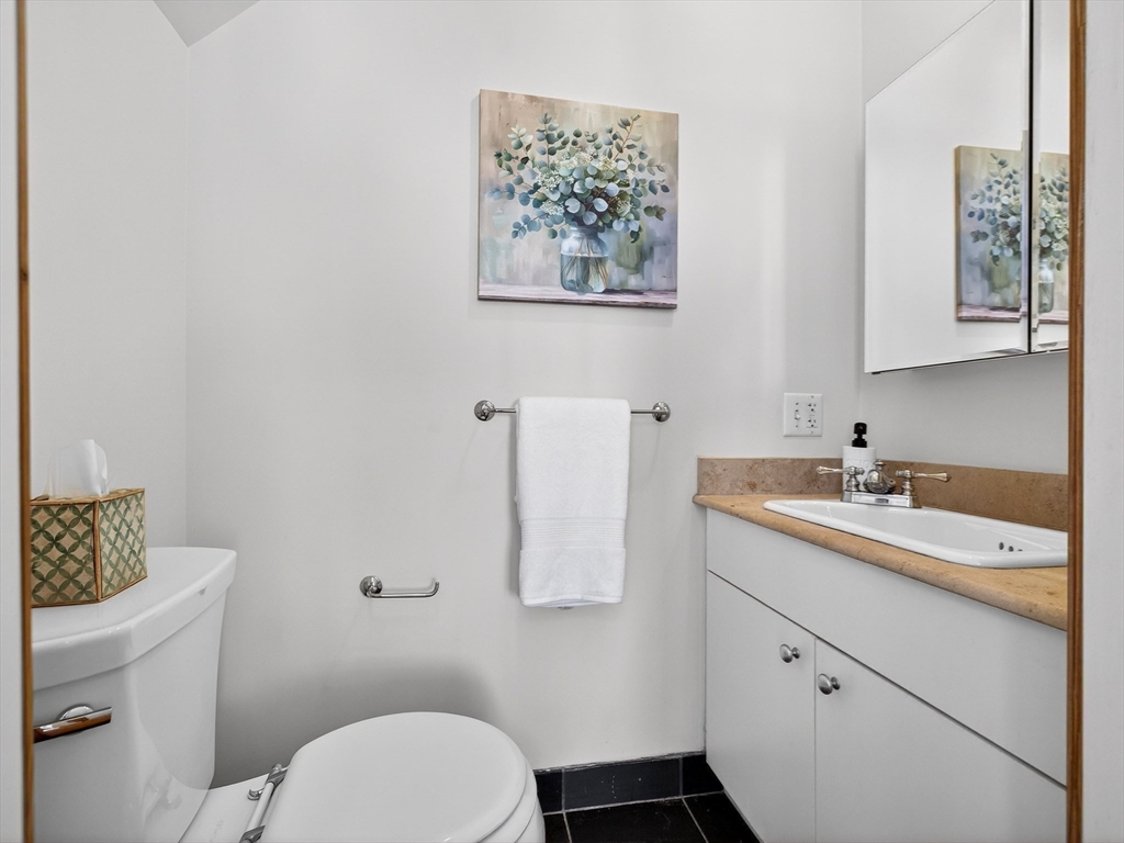 62-76 Cornwall Street, Unit 74 (E) Boston, MA 02130 - Photo 27 of 34 a bathroom with a granite countertop sink a toilet and a mirror