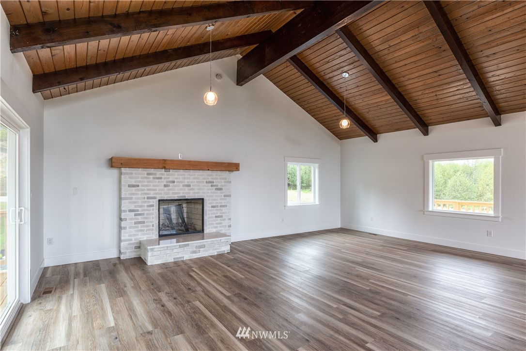 33114 Sultan Basin Road Sultan, WA 98294 - Photo 12 of 30 an empty room with wooden floor fireplace and windows
