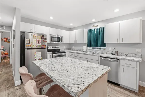 a kitchen with stainless steel appliances granite countertop a stove top oven a sink refrigerator and white cabinets