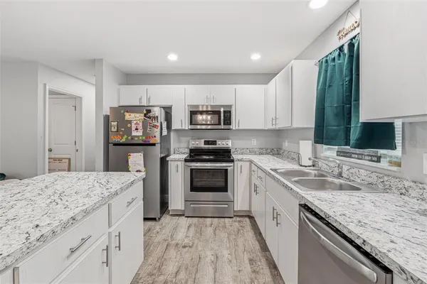 a kitchen with granite countertop a sink stove and refrigerator