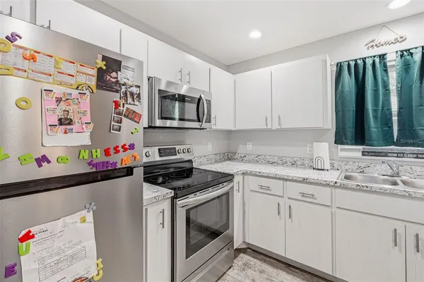 a kitchen with stainless steel appliances granite countertop a sink dishwasher and white cabinets with wooden floor