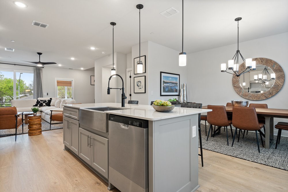 a kitchen with kitchen island granite countertop a stove a sink a island a dining table and chairs