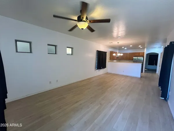 an empty room with wooden floor and a ceiling fan
