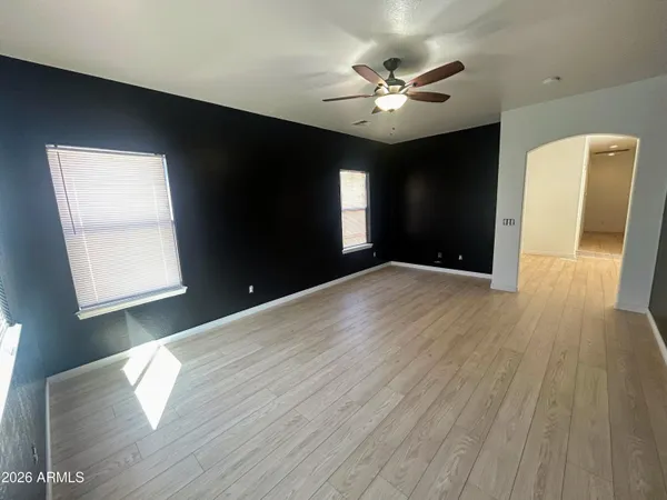 a view of an empty room with wooden floor and a window