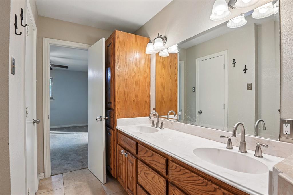 305 South Cockrell Hill Road Ovilla, TX 75154 - Photo 17 of 40 a bathroom with double vanity sinks a vanity a mirror and a shower