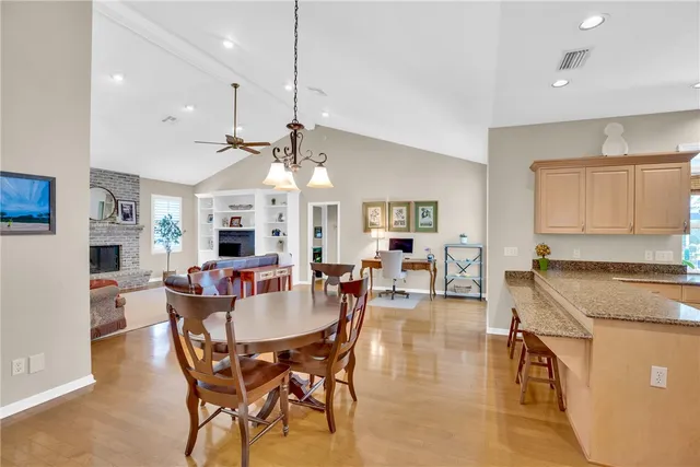 a view of a dining room and livingroom with furniture wooden floor a rug a fireplace