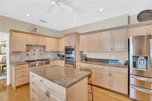 a kitchen with kitchen island granite countertop appliances cabinets and a counter space
