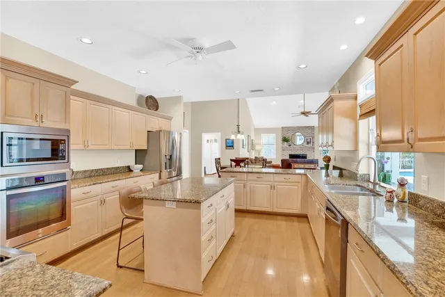 a kitchen with stainless steel appliances kitchen island granite countertop a stove top oven a sink a dining table and chairs