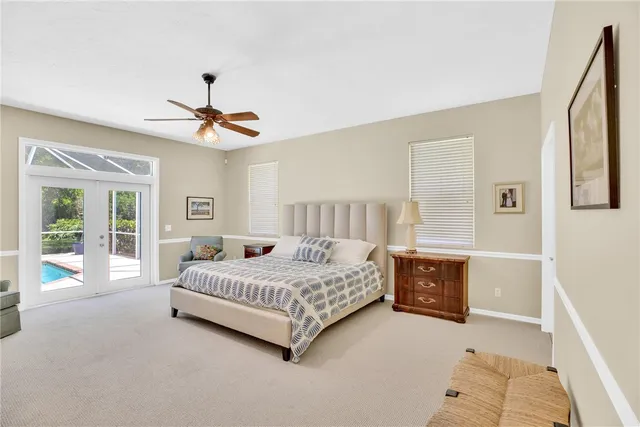 a bedroom with a large bed a chandelier and windows