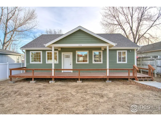 a view of a house that has a small deck and a wooden fence