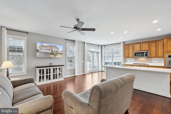 a living room with furniture wooden floor and a kitchen view