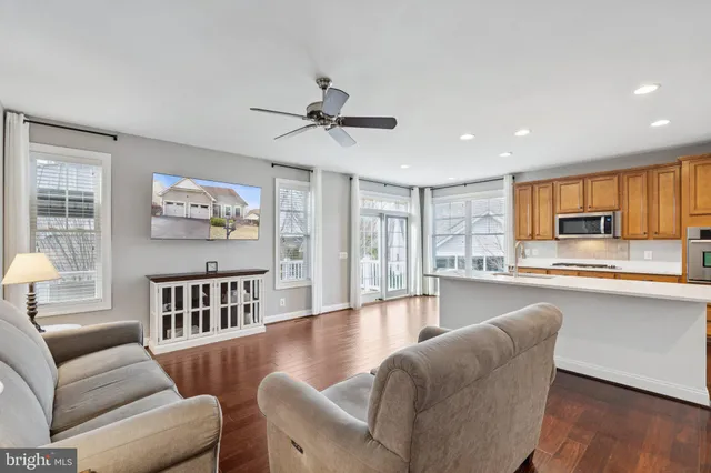 a living room with furniture wooden floor and a kitchen view