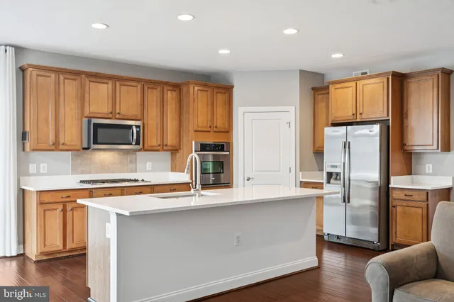 a kitchen with stainless steel appliances granite countertop a refrigerator a stove top oven a sink and dishwasher with wooden floor