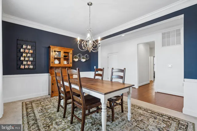 a dining room with wooden floor a chandelier a wooden table and chairs