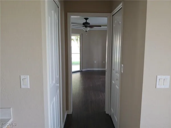 a view of a hallway with wooden floor and a bathroom
