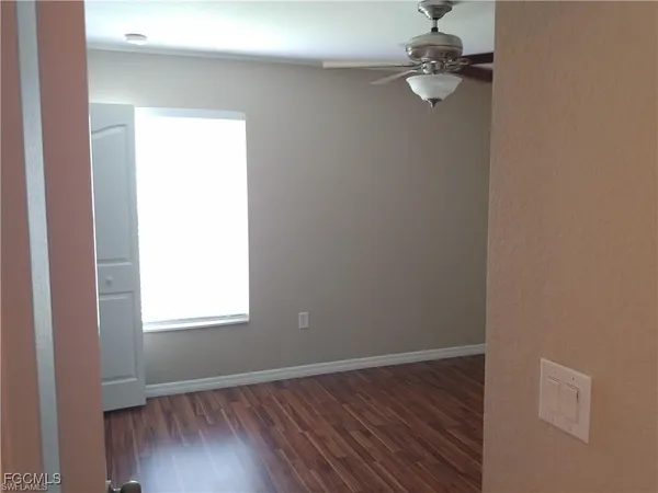 an empty room with wooden floor closet and windows