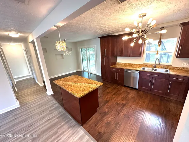 a living room with granite countertop kitchen island wooden floor dining table and sink