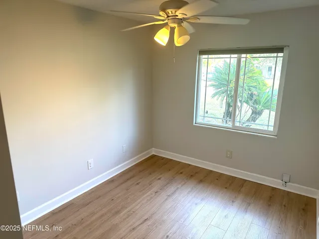 a view of an empty room with wooden floor and window