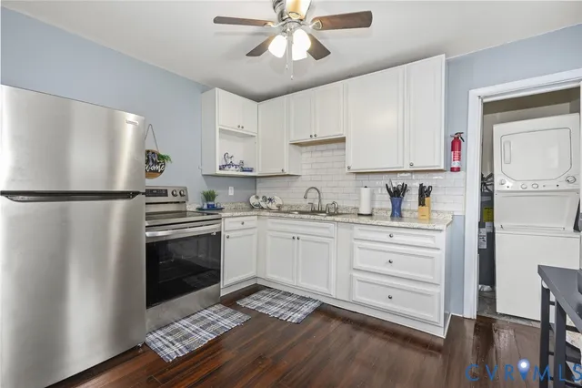 a kitchen with granite countertop a refrigerator stove and white cabinets