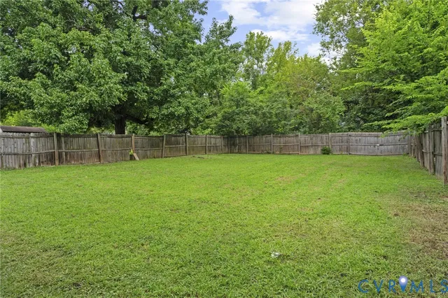 a view of a yard with a large trees and wooden fence