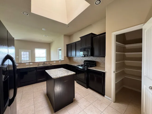 a kitchen with granite countertop stainless steel appliances a stove sink and cabinets