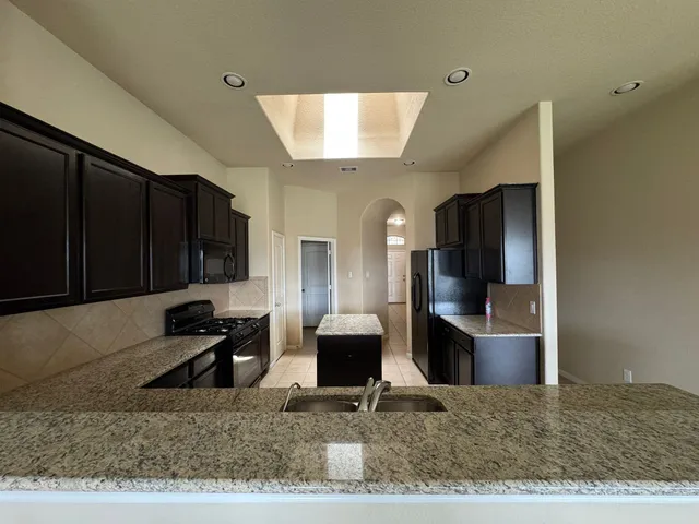 a living room with stainless steel appliances kitchen island granite countertop a rug and a view of living room