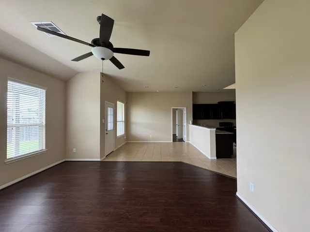 an empty room with wooden floor cabinet and windows