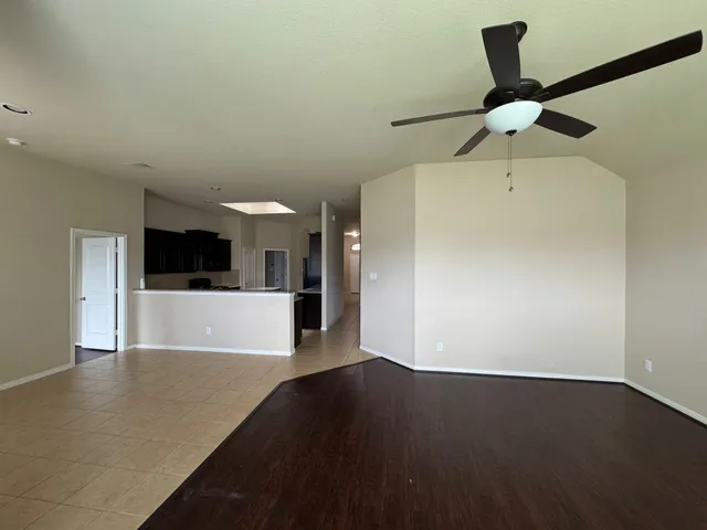 a view of a big room with wooden floor a ceiling fan and a window