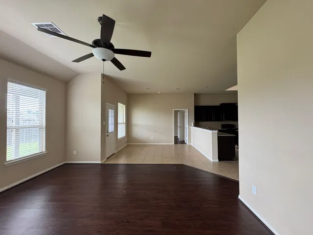 an empty room with wooden floor cabinet and windows