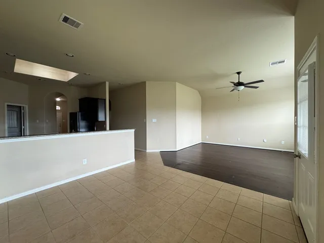 an empty room with a ceiling fan and windows