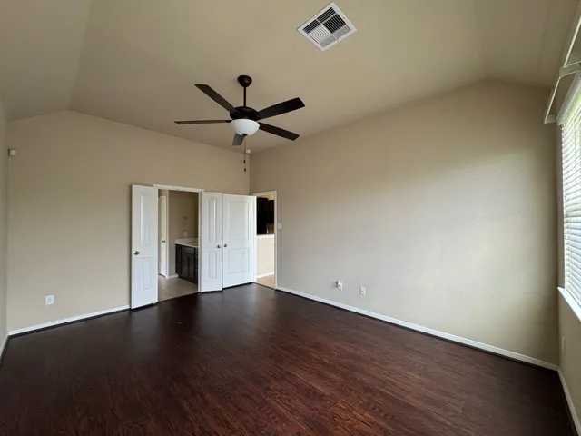 an empty room with wooden floor and ceiling fan