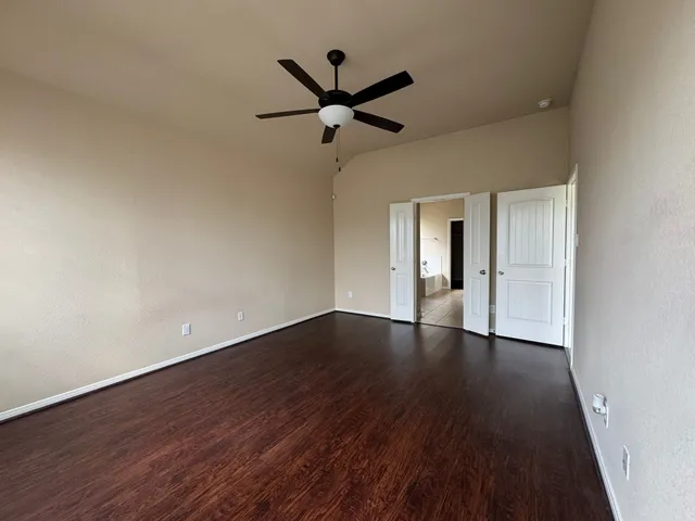 a view of empty room with wooden floor and ceiling fan