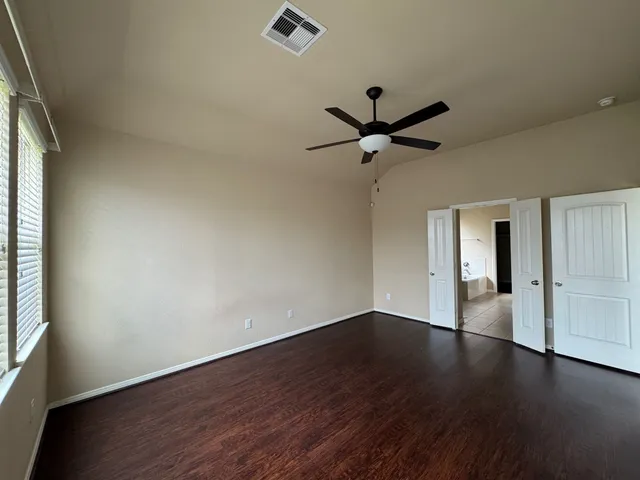 an empty room with wooden floor and windows