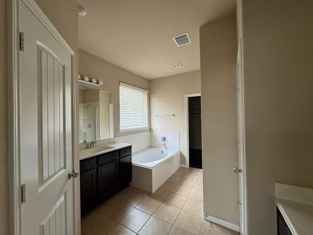 a spacious bathroom with a bathtub sink and mirror