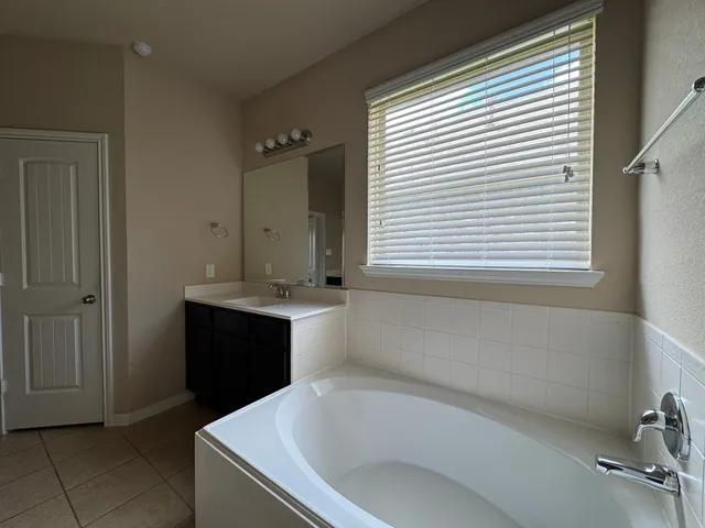 a bathroom with a tub sink and mirror