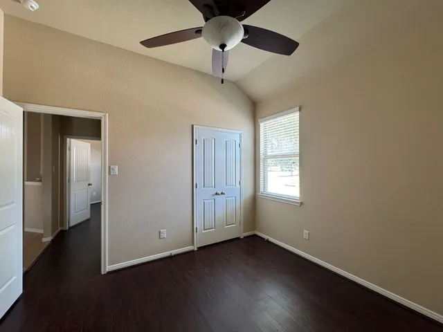 a view of an empty room with a window and wooden floor