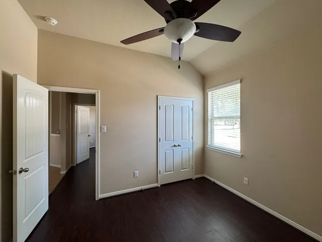 a view of an empty room with a window and wooden floor