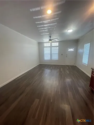 an empty room with wooden floor and windows