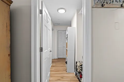 a view of a hallway with wooden floor and closet