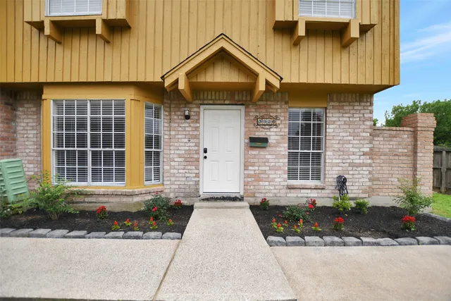 a front view of a house with a yard and potted plants