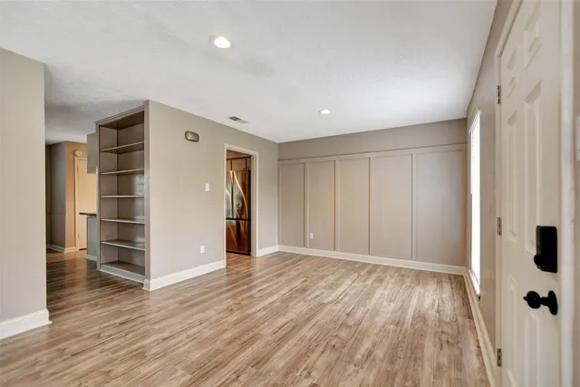 a view of empty room with wooden floor and window