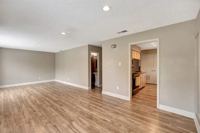 a view of a hallway with wooden floor and a kitchen space