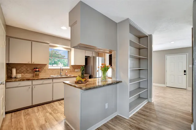 a kitchen with granite countertop stainless steel appliances a sink and refrigerator