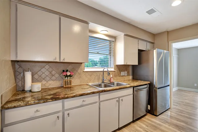 a kitchen with granite countertop a sink stove and refrigerator
