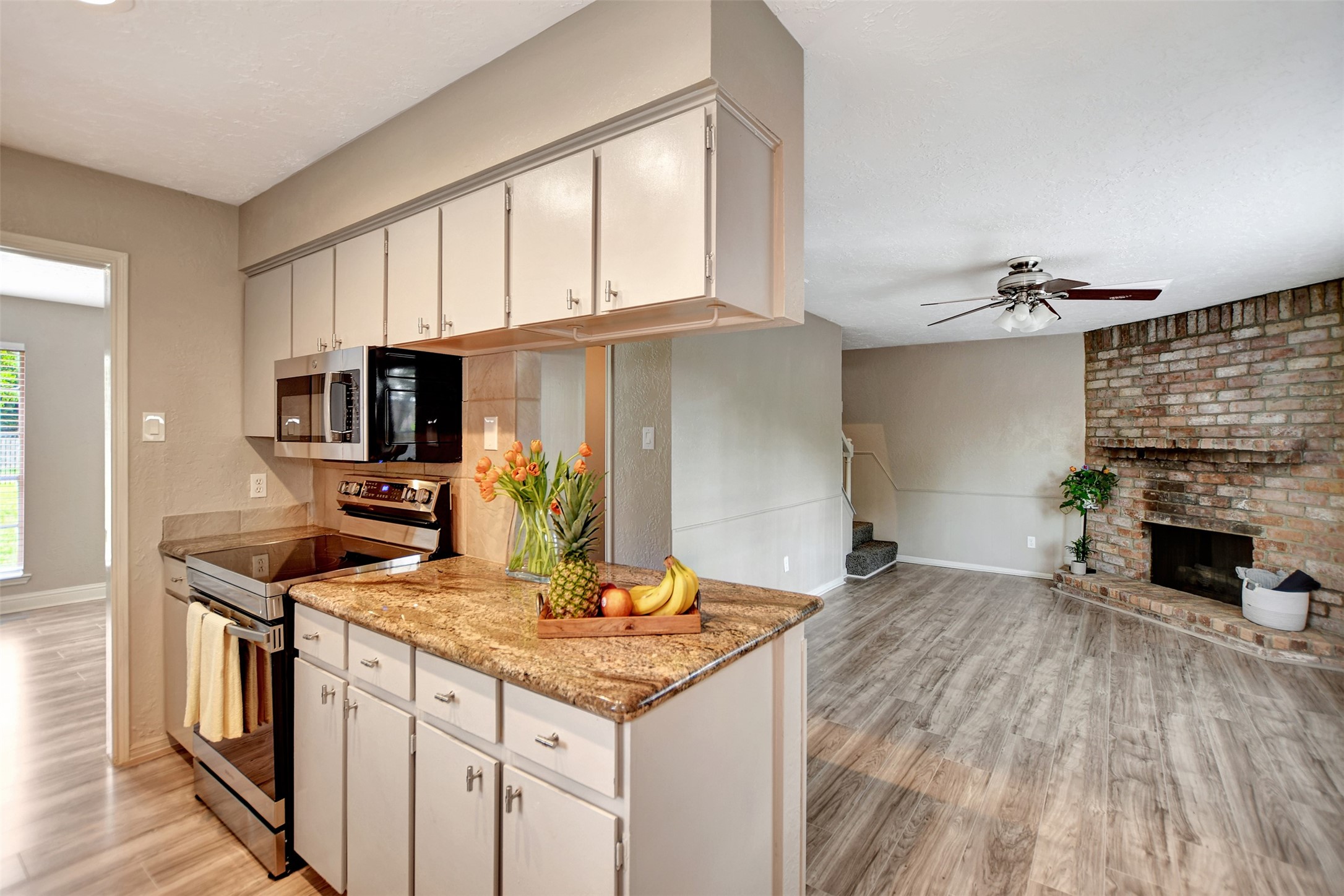 3826 Willow Springs Lane, Unit 3826 Houston, TX 77080 - Photo 27 of 43 a kitchen with kitchen island granite countertop a stove top oven a sink dishwasher and a fireplace with wooden floor